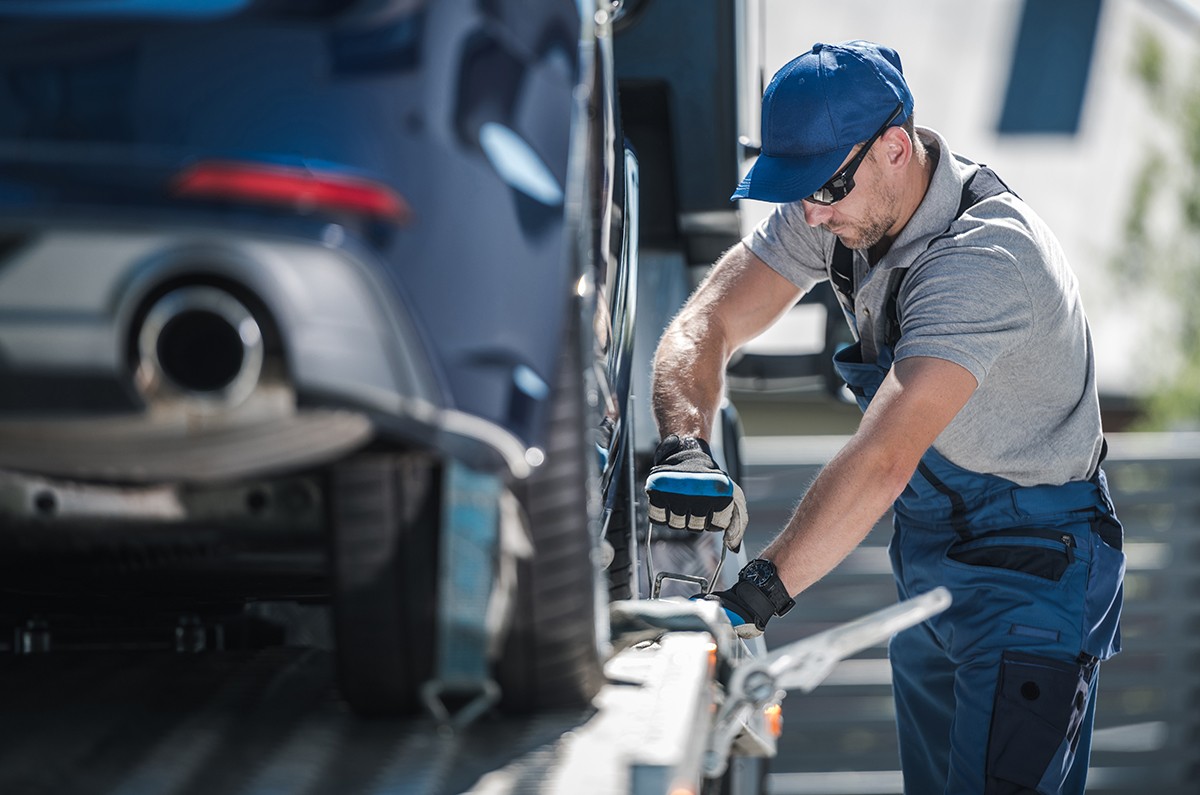 Towing Company Worker Securing Vehicle on the Truck Platform